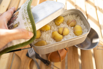 メスティンで炊いた栗ご飯の蓋をあける女性