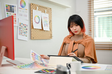 Talented Asian female graphic designer sketching a new design sample with a graphic tablet