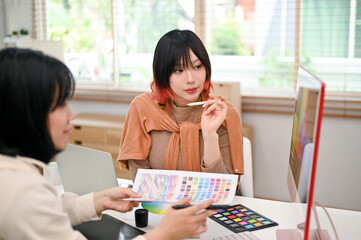 Two professional Asian female graphic designers working on their new design project