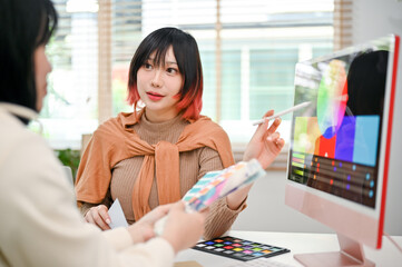 Focused Asian female graphic designer planning a new design project with her colleague