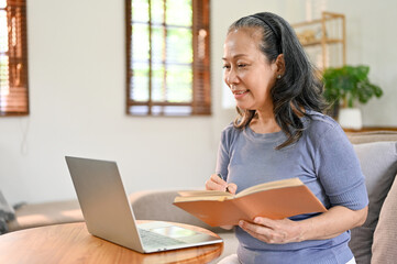 Beautiful Asian-aged retired woman is learning an online lesson at home