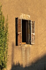 Vertical shot of an abandoned buildings with an old window with shutters
