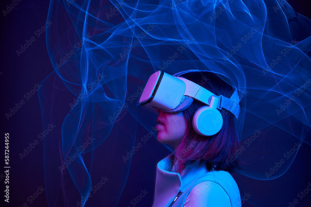 Wall mural Woman is using virtual reality headset to access in metaverse.