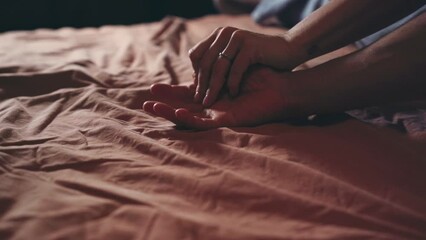 Closeup of couple hands caressing on bed