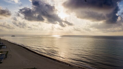 Aerial view of the sea waves touching the shore at a cloudy sunset in Mexico