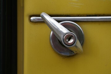 A car door handle on a yellow metal door
