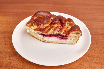 Delicious pie with cheese and cherry jam on a white plate.