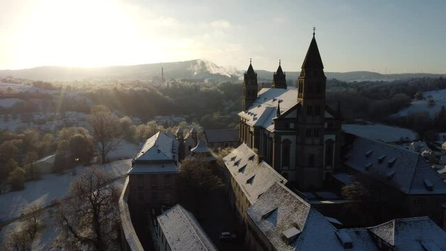 A castle that looks like Hogwarts in a winter landscape. The monastery looks like a castle, or a castle from the Middle Ages. The castle was photographed from the air with a drone