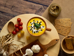 Vegetable soup in a cup on the table with decoration garlic, tomatoes, crackers, spread, food concept