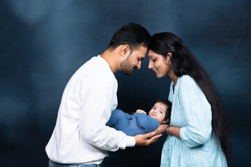 Portrait of Indian parents with newborn baby, Young asian couple holding little baby in hand. Beautiful family. Parenthood. Studio Shot.