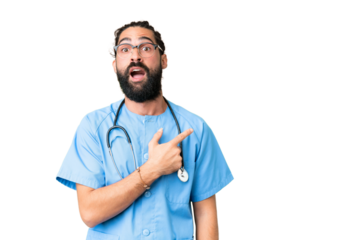 Young doctor man over isolated chroma key background surprised and pointing side