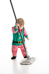 Studio photo with a white background of a baby disguised as an elf clinging to the stick of a mop
