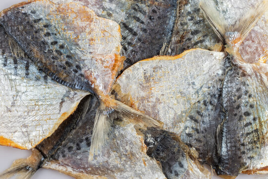 Dry salted yellowstripe scad texture background. Dried small fish pattern, selaroides snack wallpaper,