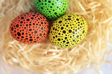 Easter eggs in the nest, top view. Happy Easter. Eggs painted in different colors with black dots.