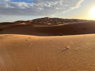 Dunes in the Sahara desert, Merzouga desert, grains of sand forming small waves on the dunes, panoramic view. Setting sun. Morocco
