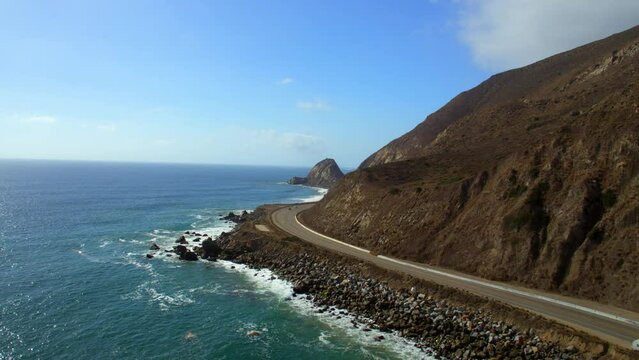 Aerial Shot Of Vehicles Moving On Mountain Road, Drone Flying Forward Over Sea During Sunny Day - Camarillo, California