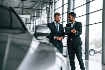 Checking quality of the vehicle. Man is consulting the customer in the car showroom