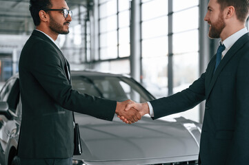 Two businessmen are working together in the car showroom