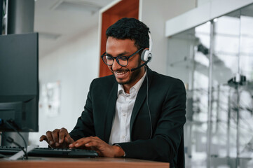 Indian man is sitting and working in the car showroom