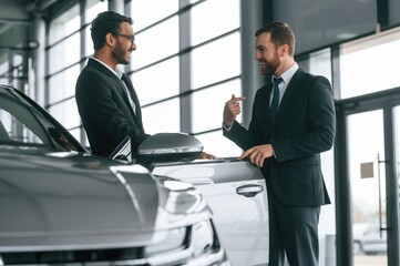 Two businessmen are working together in the car showroom