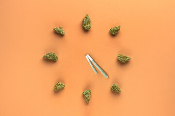 Joints with cannabis in the form of clock hands, dry marijuana buds represent the numbers of the clock.  The arrows indicate the time 4:20 pm.  On a light brown background