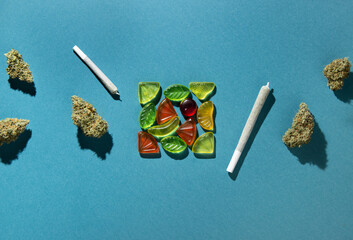 Gummy fruits lie in a square in the center, dry buds of medical marijuana and joints lie to the...