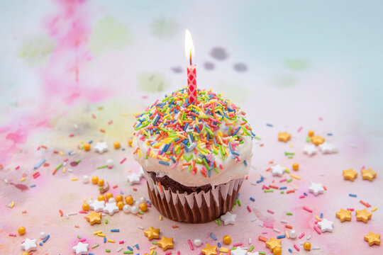 Cupcake mit Kerze und Zuckerstreuseln