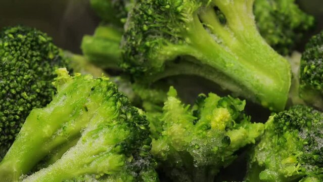 Green frozen broccoli stew in a saucepan. steam from frozen vegetables