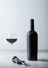 Bottle and glass of red wine with cork on light background.