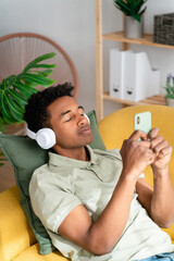 Black man in headphones using smartphone at home