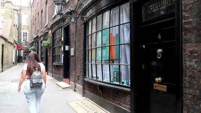 Young woman walking through Goodwin's Court in Westminster borough at day time. Harry Potter setting