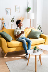 Obraz premium Cheerful black woman with cup of coffee