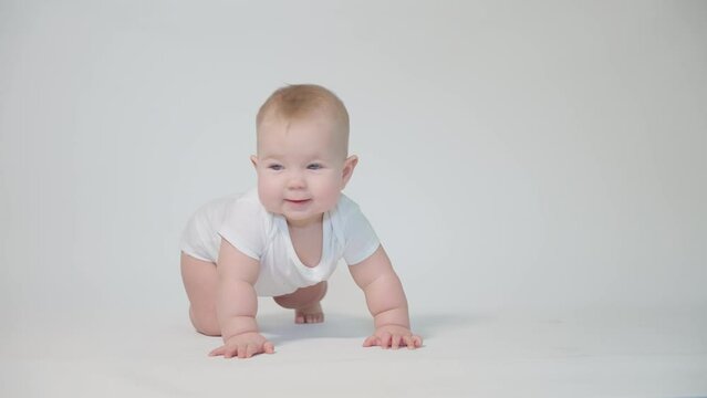 infant on white background first attempts to crawl on his knees