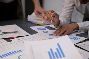 Teamwork of asian business people discussing and calculating with calculator on evaluation data in...