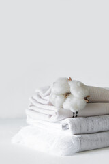 Fototapeta na wymiar Cotton branch with pile of folded bed sheets and blankets.Organic lifestyle and skin care products