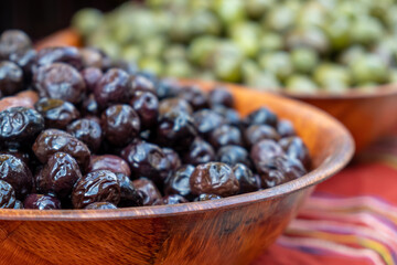 Green and black olives in wooden bowls