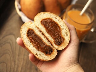 hand holding bread bun with Thai milk tea custard cream