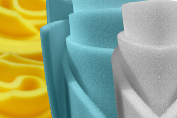 rolls of white, turquoise and yellow foam sponge. circular bundle. textured sheer sofa material. rolled polyurethane in industry - obrazy, fototapety, plakaty