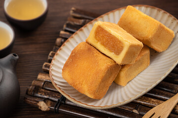 Delicious pineapple cake pastry in a plate on wooden table background with tea.