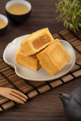 Delicious pineapple cake pastry in a plate on wooden table background with tea.