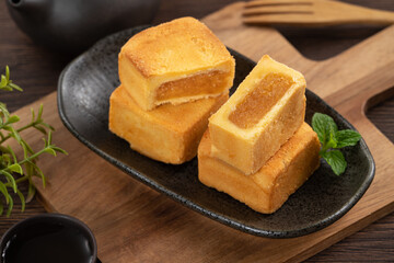 Delicious pineapple cake pastry in a plate on wooden table background with tea.