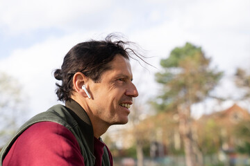 man listening to music with wireless headphones in a park during spring