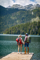 Hiking couple. Young man and girl with backpacks at lake