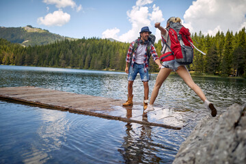 travel hikers in love enjoying the nature while playing with water in the lake of the mountain.