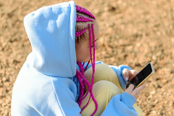 Close-up of a caucasian teenage girl with pink braids using smartphone.Technology,summer...