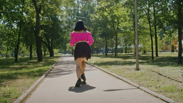 playful girl enjoys summer and rides a scooter through the park and city streets.