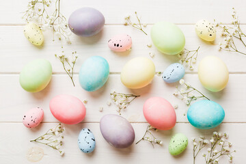 Fototapeta na wymiar Happy Easter composition. Easter eggs on colored table with gypsophila. Natural dyed colorful eggs background top view with copy space