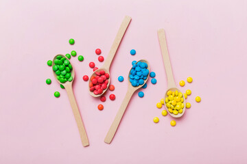delicious colorful sweet candies on spoon on colored background . Confectionery decor top view with...