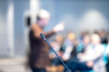 Blurred public speaker gesturing and using nonverbal communication during presentation, conference,...