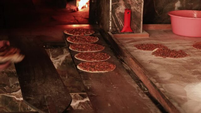 Traditional Turkish dish called "lahmacun" is being made in a bakery using wood fire.